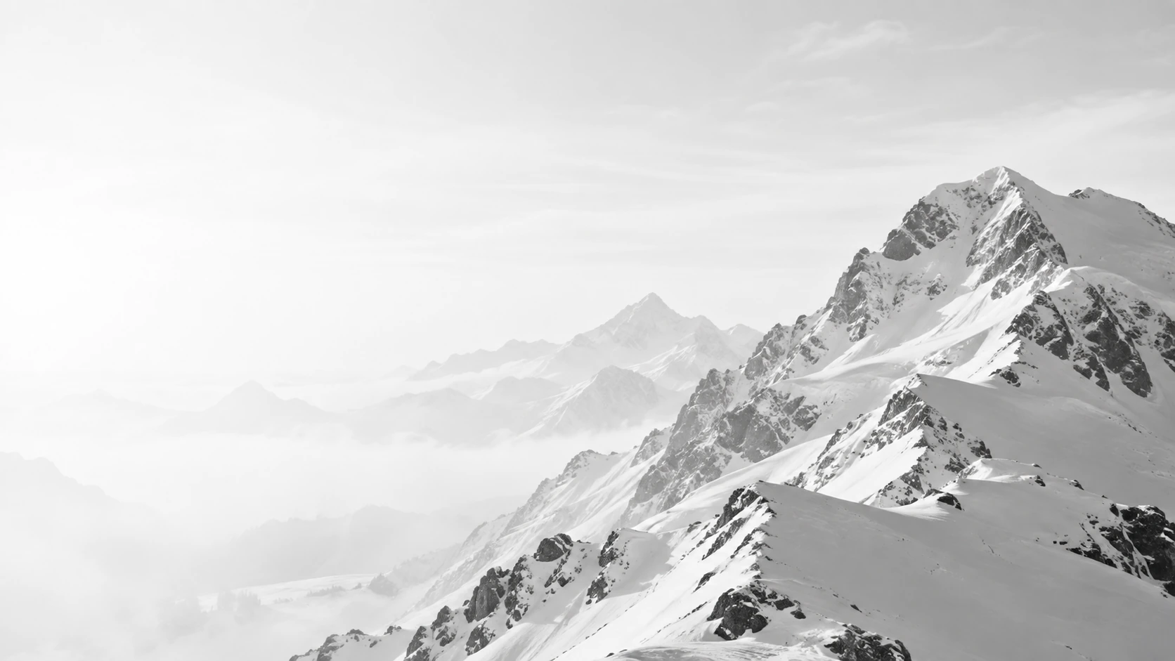 Black-and-white snow-capped mountain peaks beneath a bright, open sky